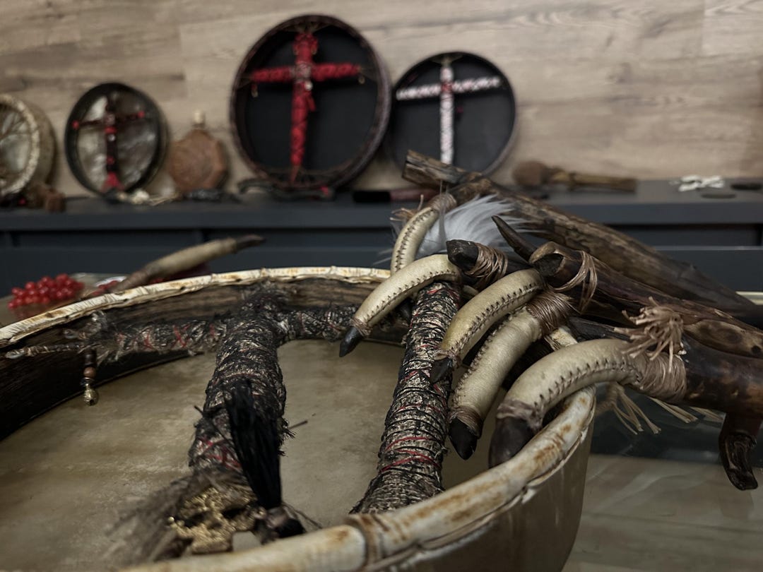 Shaman's finger rattles with a frame drum, crosses on the wall behind